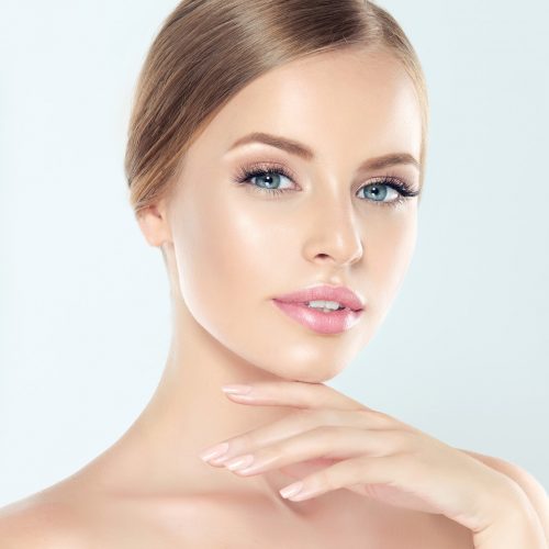 Young  blond-haired woman with clean fresh skin and soft, delicate make up. Woman  is touching tenderly to own face. Image of freshness and cleanliness.Cosmetology, plastic surgery,facial treatment and beauty technologies.